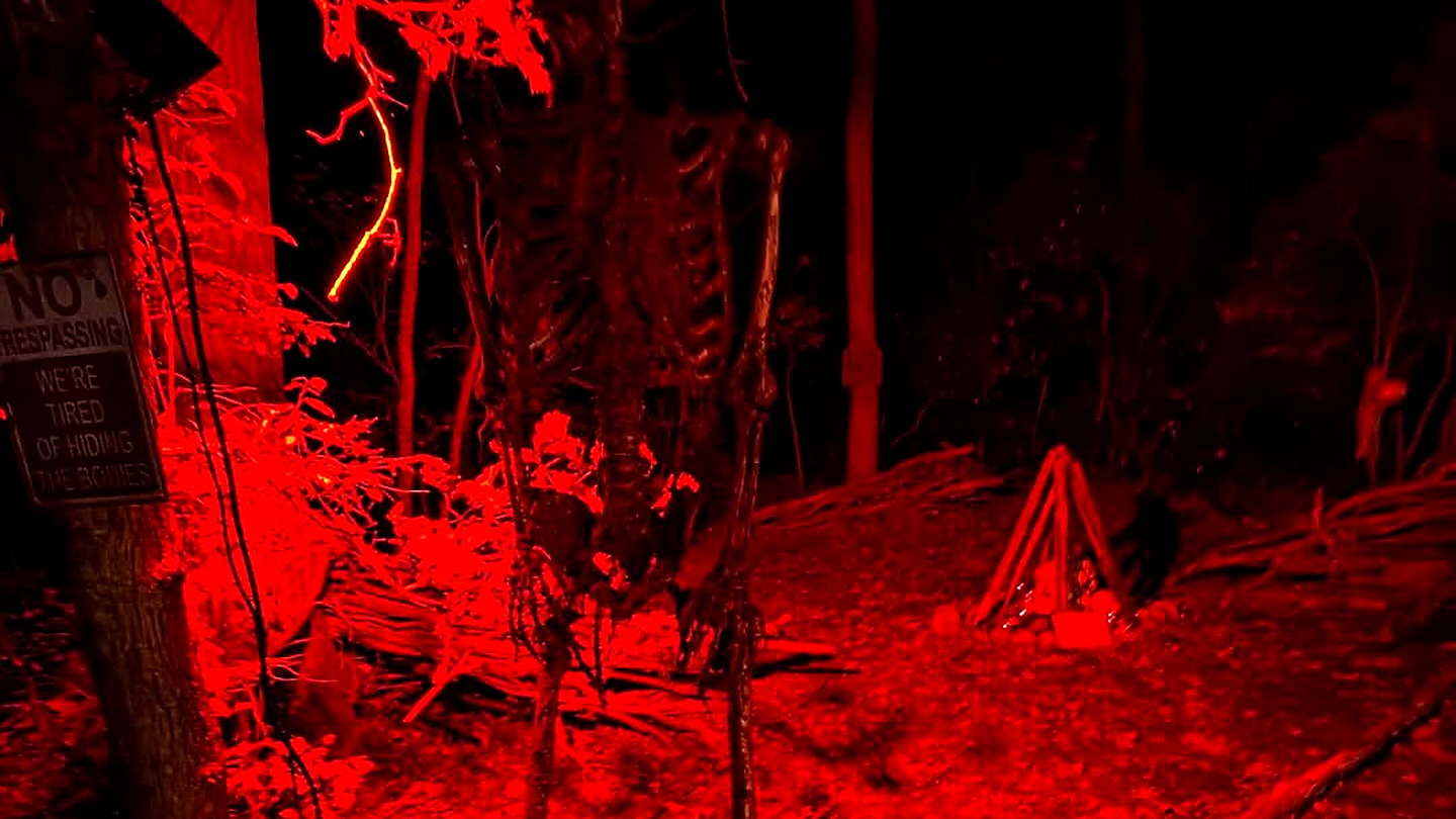 Scare actor with lantern on the night trail